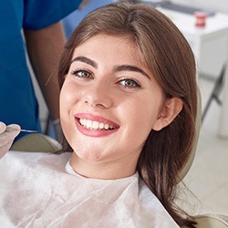 Smiling woman in dental chair for dental checkup to prevent dental emergencies