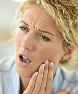 Woman holding jaw in pain before root canal therapy