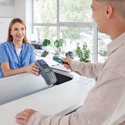 Patient providing payment at dental office front desk