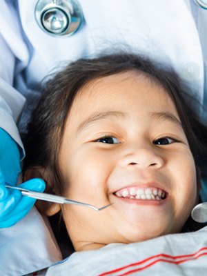 Little girl smiling as dentist examines her teeth