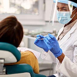 Smiling dentist wearing PPE during exam