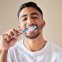 Man smiling while brushing his teeth