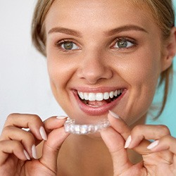 Woman smiling while holding whitening tray
