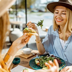 Two friends smiling while eating lunch outside