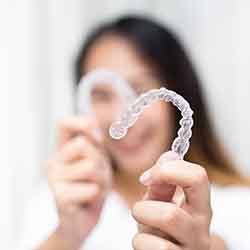 Smiling patient holding clear aligners