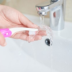 Patient using toothbrush to clean aligner